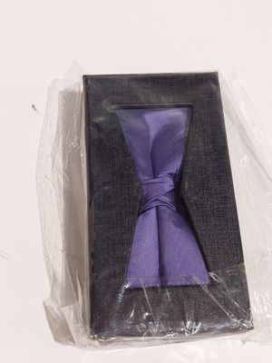 une cravate violette dans une boîte noire posée sur une surface blanche