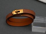 leather bracelet with a gold buckle on a clear acrylic block