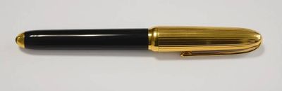 une image représentant un stylo noir et doré posé sur une surface blanche