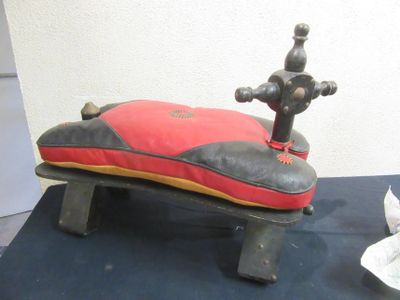 a red and black pillow on top of a wooden bench