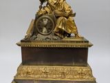 a gold statue of a woman sitting on top of a clock