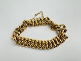 a close up of a gold chain bracelet on a white surface