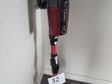 un aspirateur rouge et noir posé contre un mur blanc