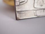 a silver plate that has a picture of a suitcase on it