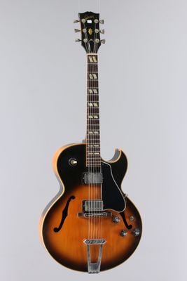 un gros plan d'une guitare posée sur un support, sur fond blanc