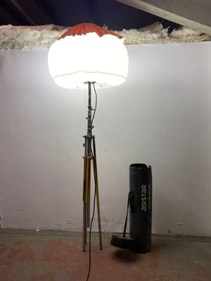 une lampe posée sur un trépied à côté d'un sac