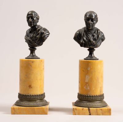 a pair of bronze busts of a man and a woman on marble bases
