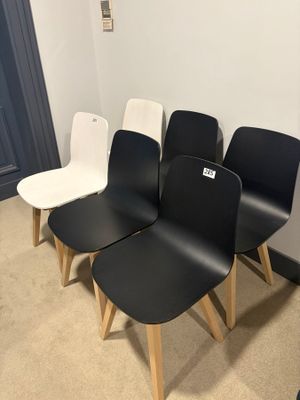 four black and white chairs are lined up against a white wall
