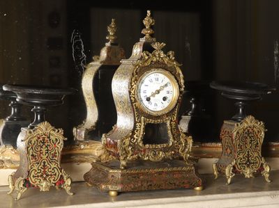 a clock sitting on top of a mantle next to a mirror