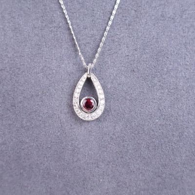 a silver necklace with a red stone in the center
