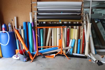 de nombreux rouleaux de tissu posés par terre à côté d'un présentoir