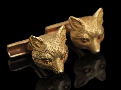 Boutons de manchette représentant une tête de renard dorée sur fond noir avec un reflet