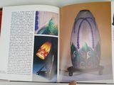 someone is holding a book open to show a picture of a vase