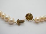 un gros plan sur un collier de perles muni d'un fermoir en or