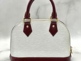 a white and maroon handbag with two handles on a marble surface