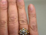 a woman ' s hand holding a gold and diamond ring
