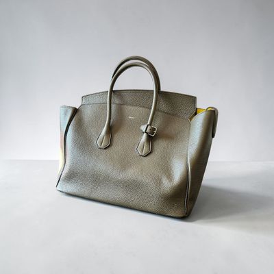 un gros plan d'un sac à main posé sur une surface blanche