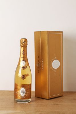 une photo représentant une bouteille de champagne posée à côté d'une boîte sur une table
