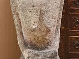 une statue représentant un homme assis sur une table, à côté d'une commode