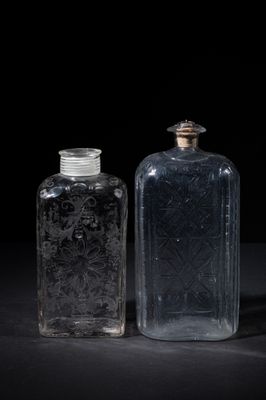 two clear glass bottles sitting next to each other on a black surface