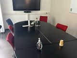 une table noire avec des chaises rouges et une télévision en arrière-plan