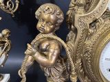 a gold clock with a statue of a boy holding a bird