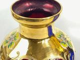 a red vase with gold decoration on it on a white surface