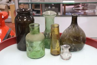 several different colored glass vases on a red tray in a glass case