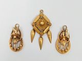 trois bijoux en or sont exposés sur un fond blanc