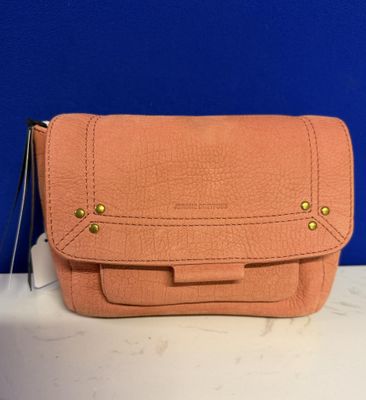 un sac à main en cuir rose avec des finitions dorées, posé sur un comptoir blanc