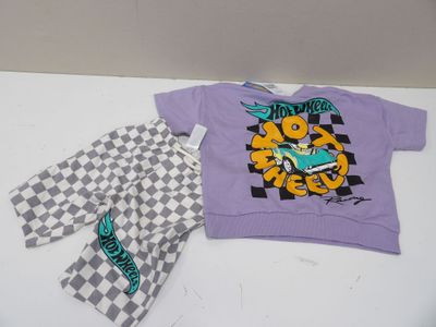 une chemise violette et un pantalon à carreaux posés sur une table blanche