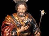 a statue of jesus holding a staff and a flower
