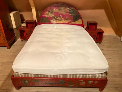 un lit avec une tête de lit rouge et un drap blanc posé dessus
