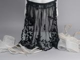 une photo d'un mannequin portant une robe noire ornée de voiles transparents