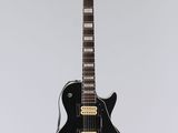 une guitare électrique noire accrochée à un mur blanc