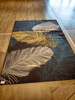 a black rug with white and gold feathers on it