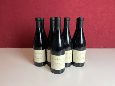 six bouteilles de vin sont posées sur une table devant un mur rouge