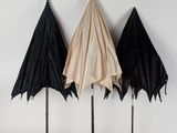 three umbrellas are lined up against a white wall in a row