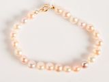 a close up of a pearl bracelet on a white surface