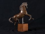statue of a horse standing on its hind legs on a wooden base