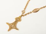 a close up of a gold necklace with a cross on it