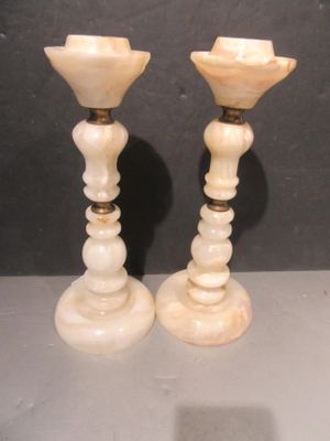 pair of white marble candlesticks on a table with a black background