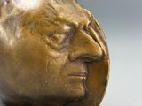 une statue en bronze représentant le visage d'un homme posée sur une table