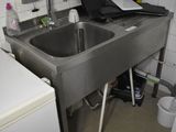 a small kitchen with a sink and a laptop on the counter