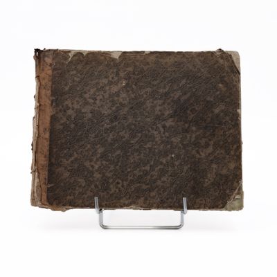 an old book on a metal stand on a white surface