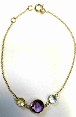 a close up of a gold chain bracelet with a purple stone