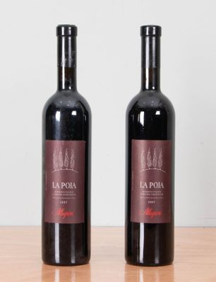 two bottles of red wine sitting on top of a wooden table