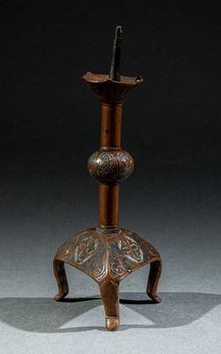 un vieux bougeoir en bronze orné d'un motif floral sur le dessus