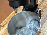 a metal bowl with ice in it on a wooden table