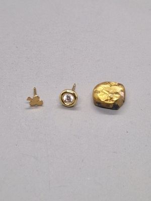 deux clous en or et un petit diamant sur un fond blanc